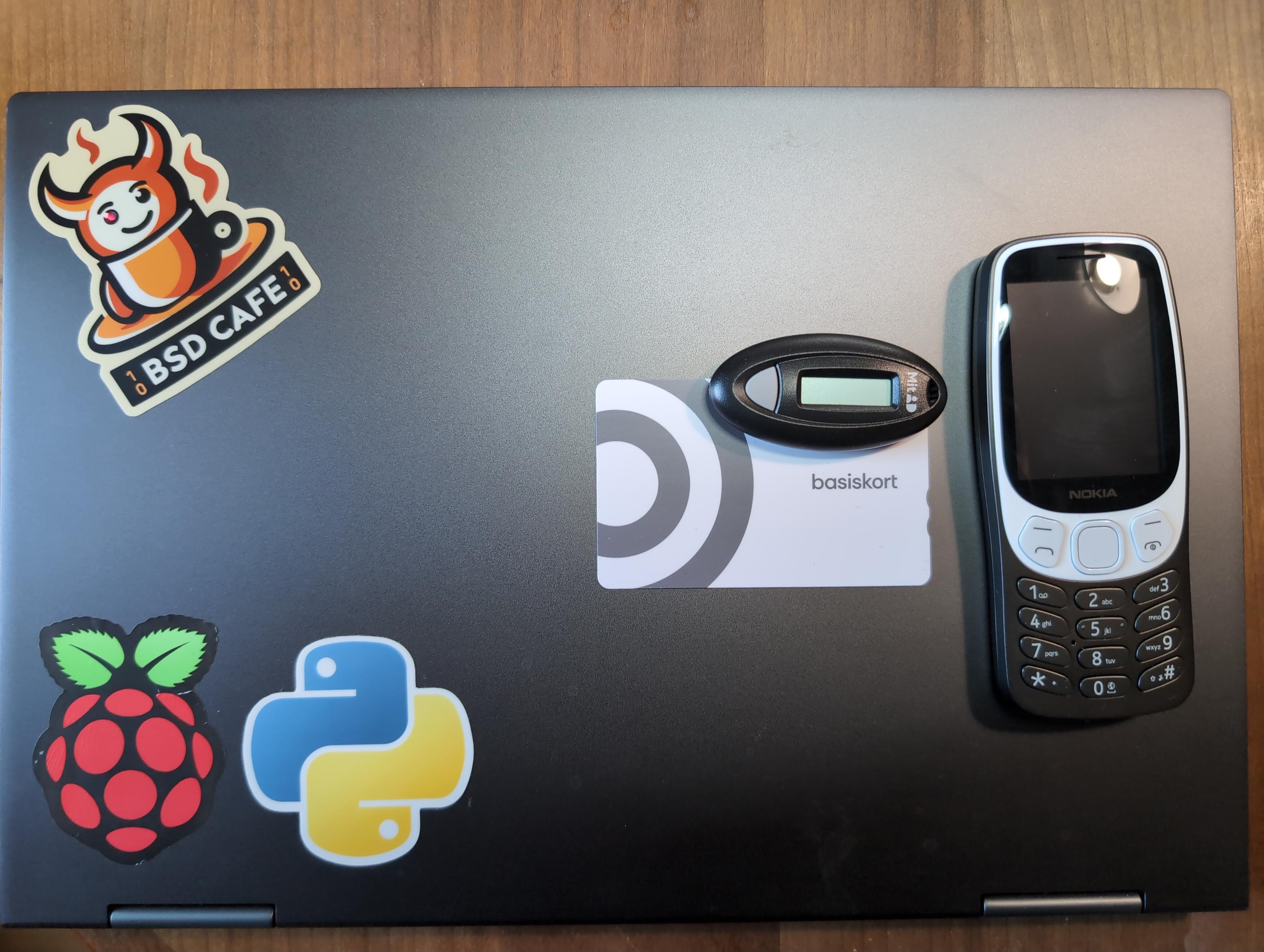 Laptop med FreeBSD, ovenpå ligger kodeviser, basiskort og mobiltelefon